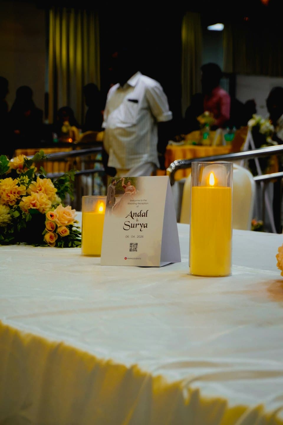 Un bouquet floreale e candele accese decorano un tavolo per ricevimenti nuziali.