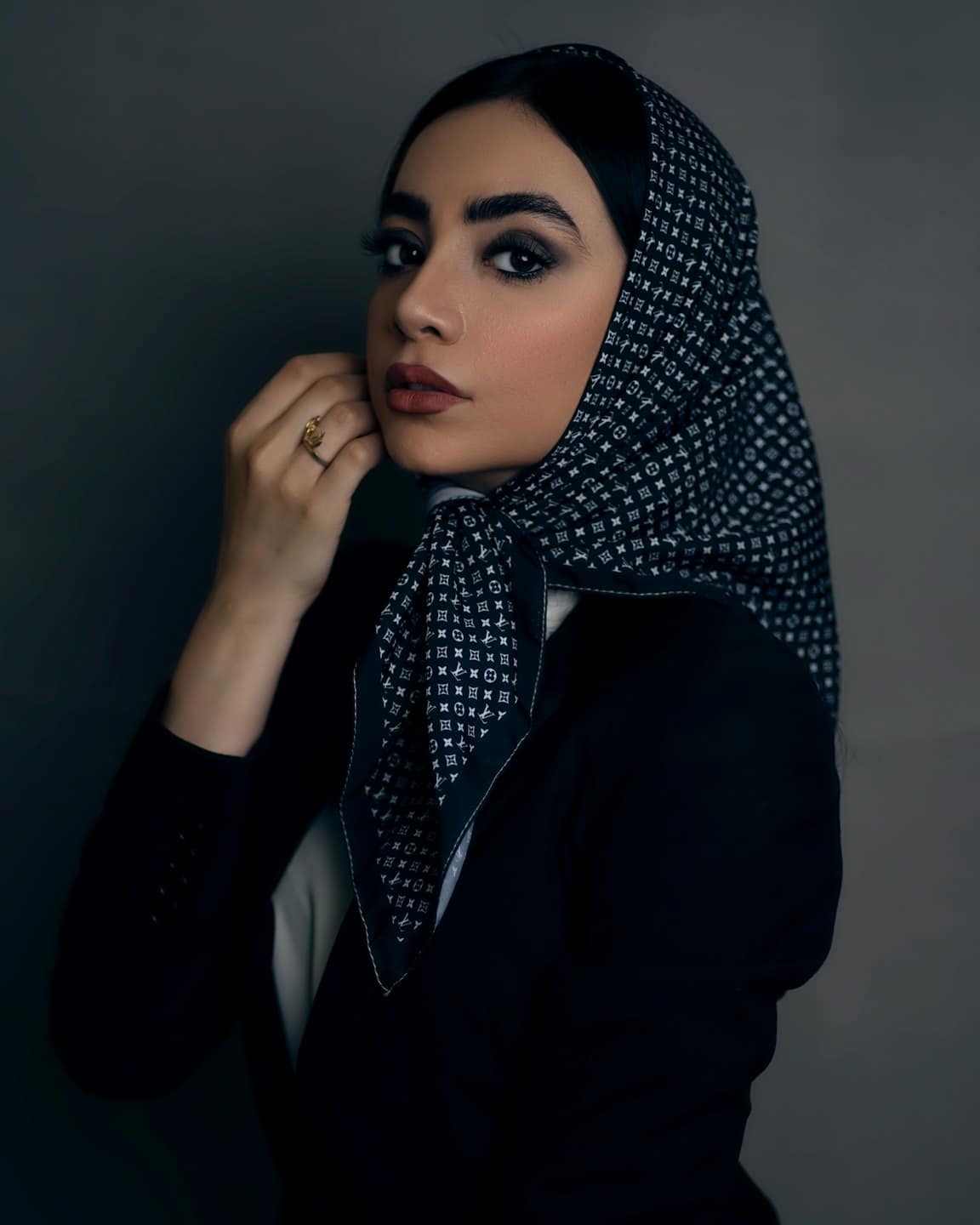 Giovane donna sistema il suo foulard fantasia indossando un blazer.